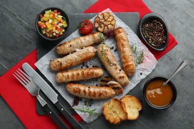 Tasty fresh grilled sausages served with vegetables on grey table, flat lay