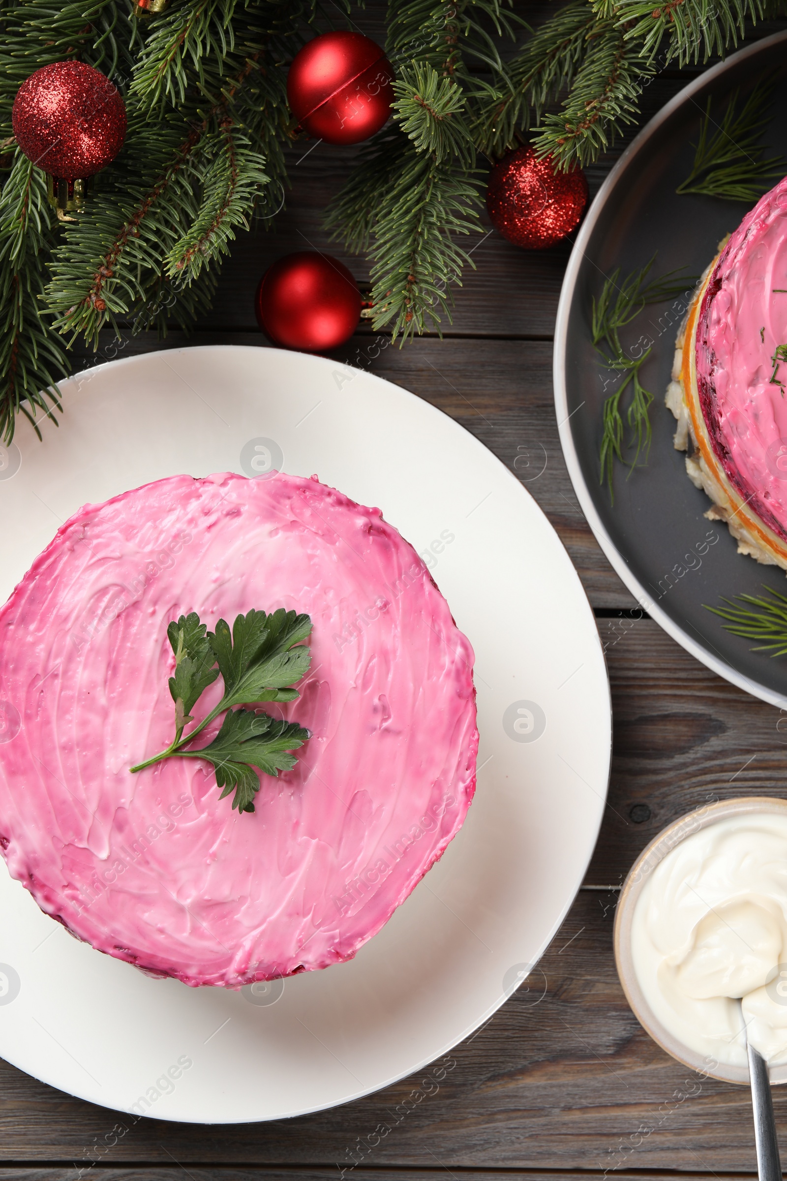 Photo of Herring under fur coat salad and Christmas decor on wooden table, flat lay. Traditional Russian dish