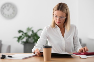 Photo of Woman working with documents at wooden table in office