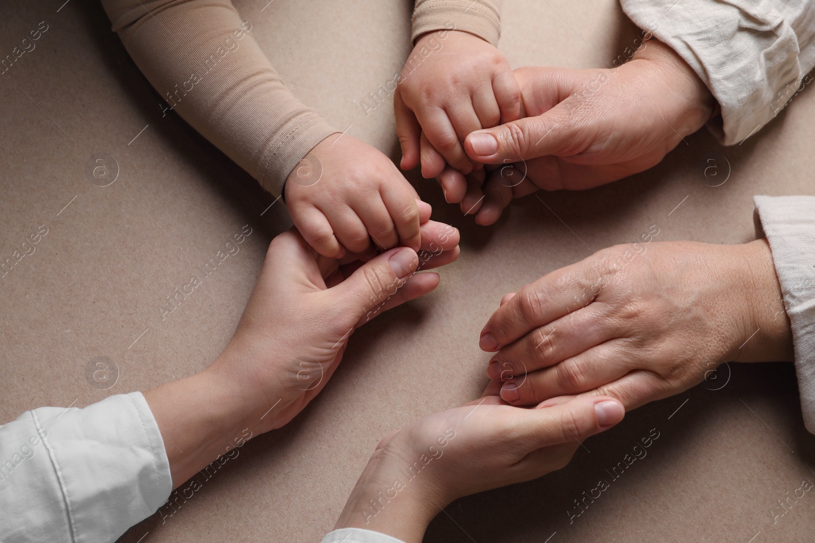 Photo of Family holding hands together on brown background, above view