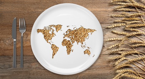 Image of Global food crisis concept. World map made of wheat grains in plate, cutlery and spikes on wooden table, flat lay
