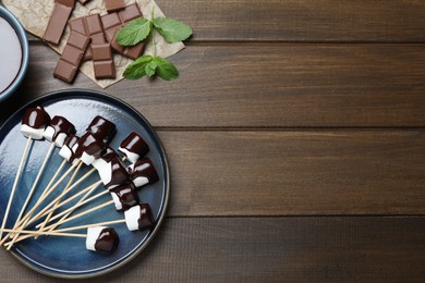 Photo of Delicious marshmallows covered with chocolate on wooden table, flat lay. Space for text