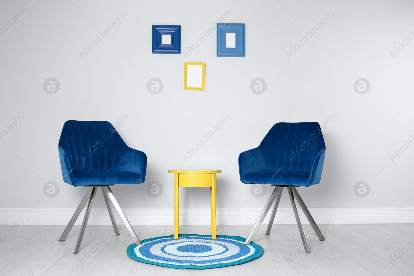 Photo of Stylish chairs and side table near white wall. Idea for interior design