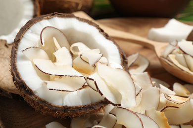 Photo of Tasty coconut chips and nut on wooden plate, closeup
