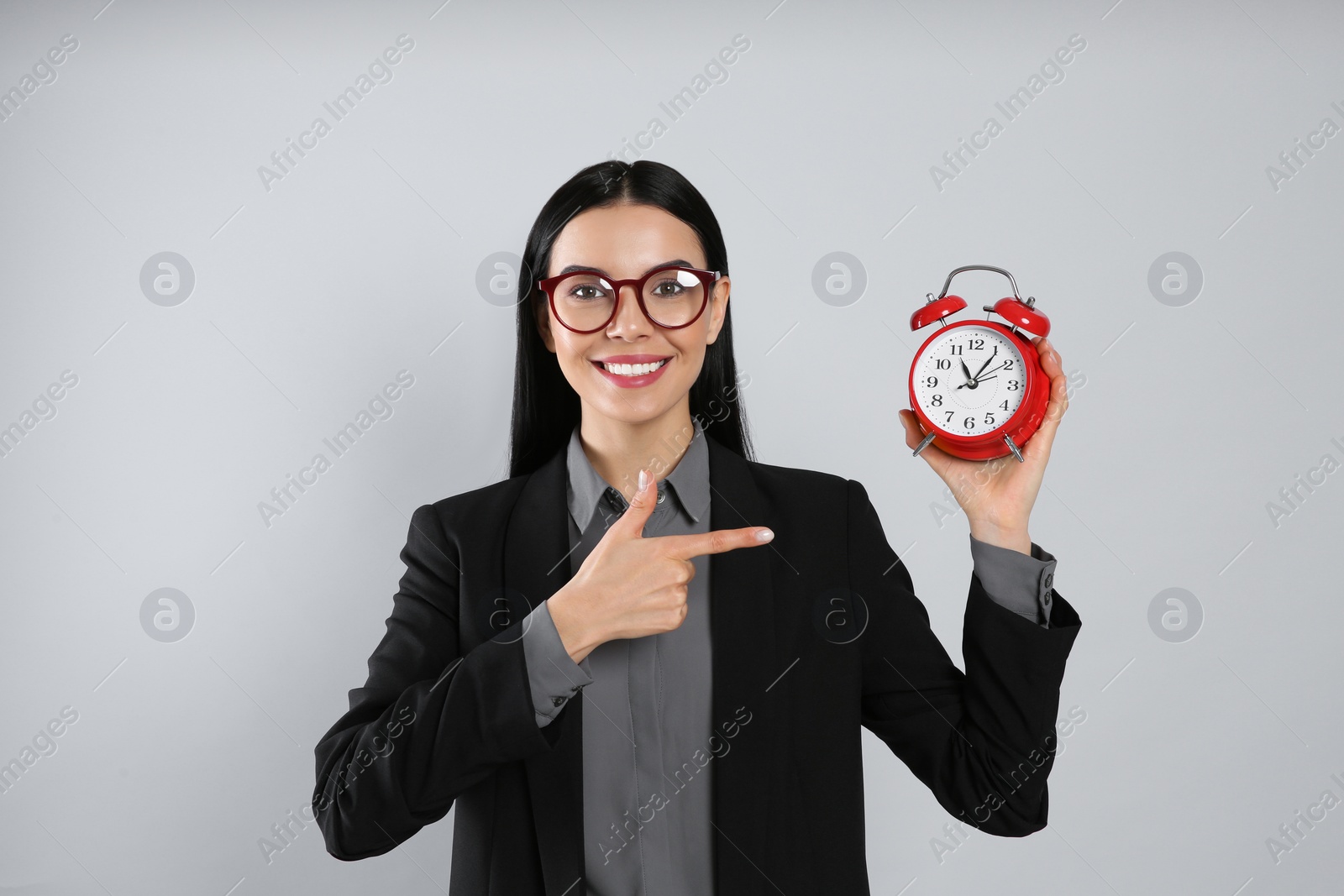 Photo of Businesswoman holding alarm clock on light grey  background. Time management