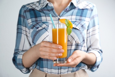 Photo of Woman with natural peach juice on light background, closeup