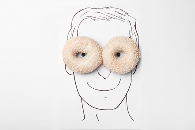 Photo of Drawing of man's face and tasty donuts on white background, top view