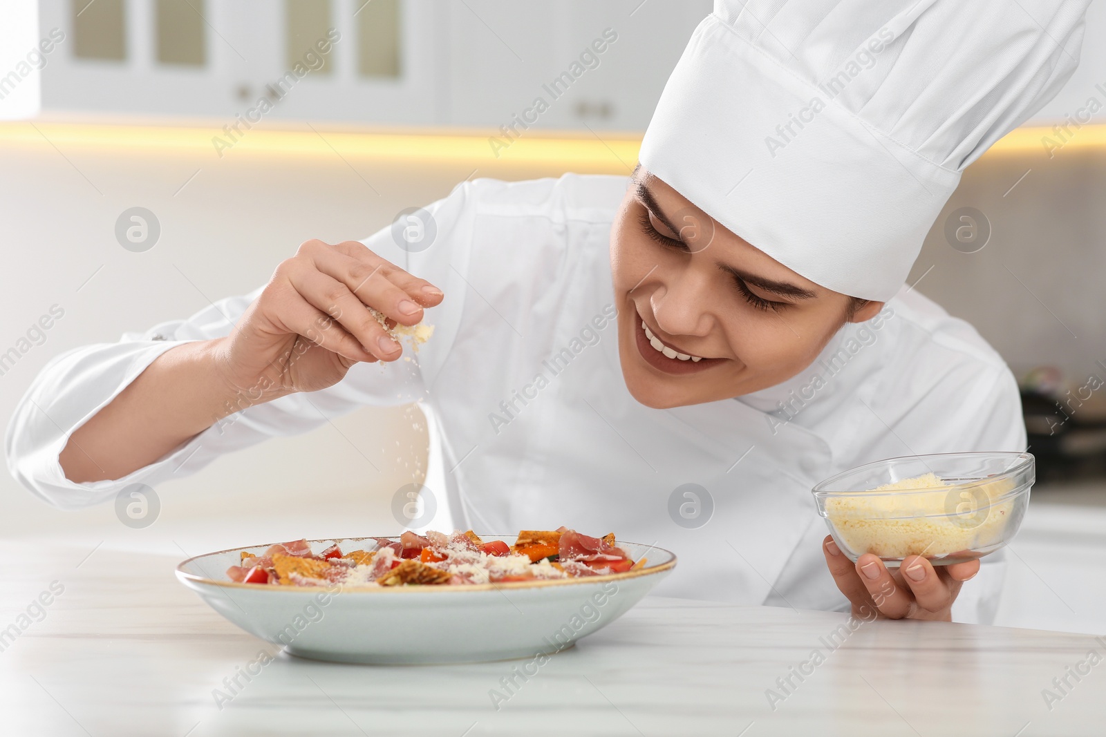 Photo of Professional chef adding grated cheese into delicious dish in kitchen