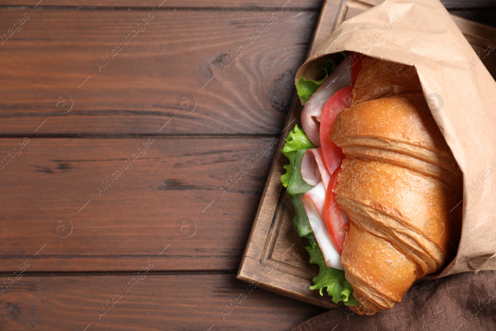 Photo of Tasty croissant sandwich with ham on wooden table, top view. Space for text