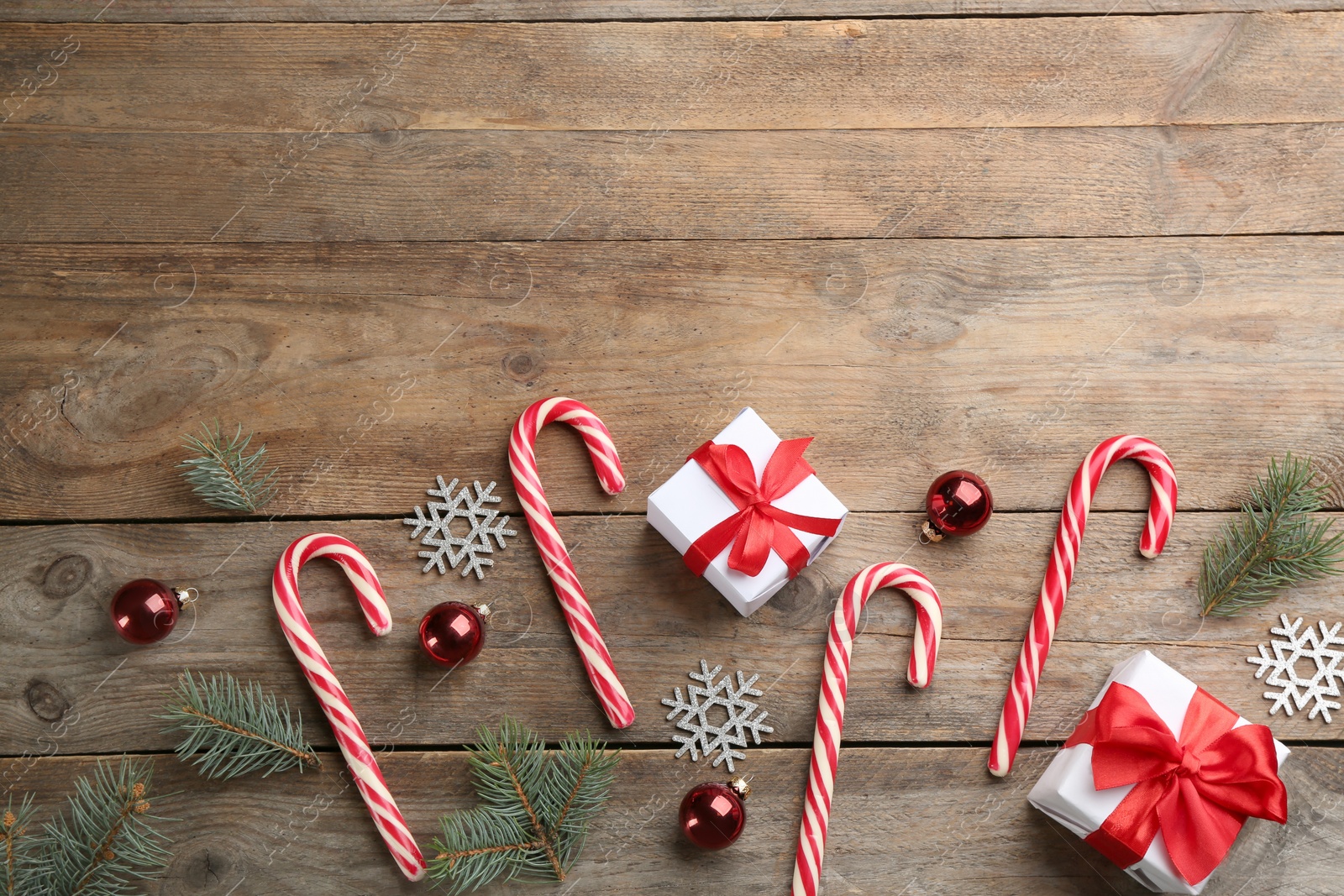 Photo of Flat lay composition with candy canes and Christmas decor on wooden background. Space for text