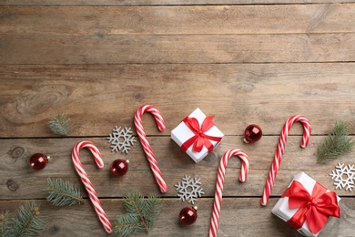 Photo of Flat lay composition with candy canes and Christmas decor on wooden background. Space for text