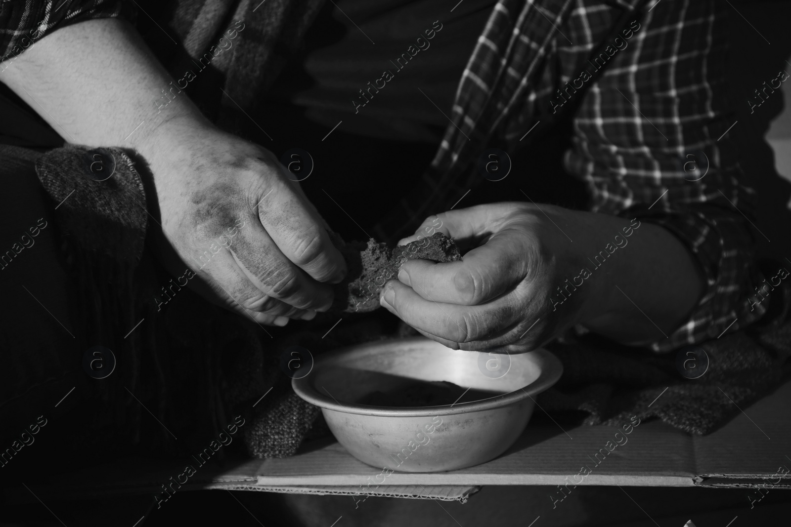 Photo of Poor senior man with bowl and bread, closeup. Black and white effect