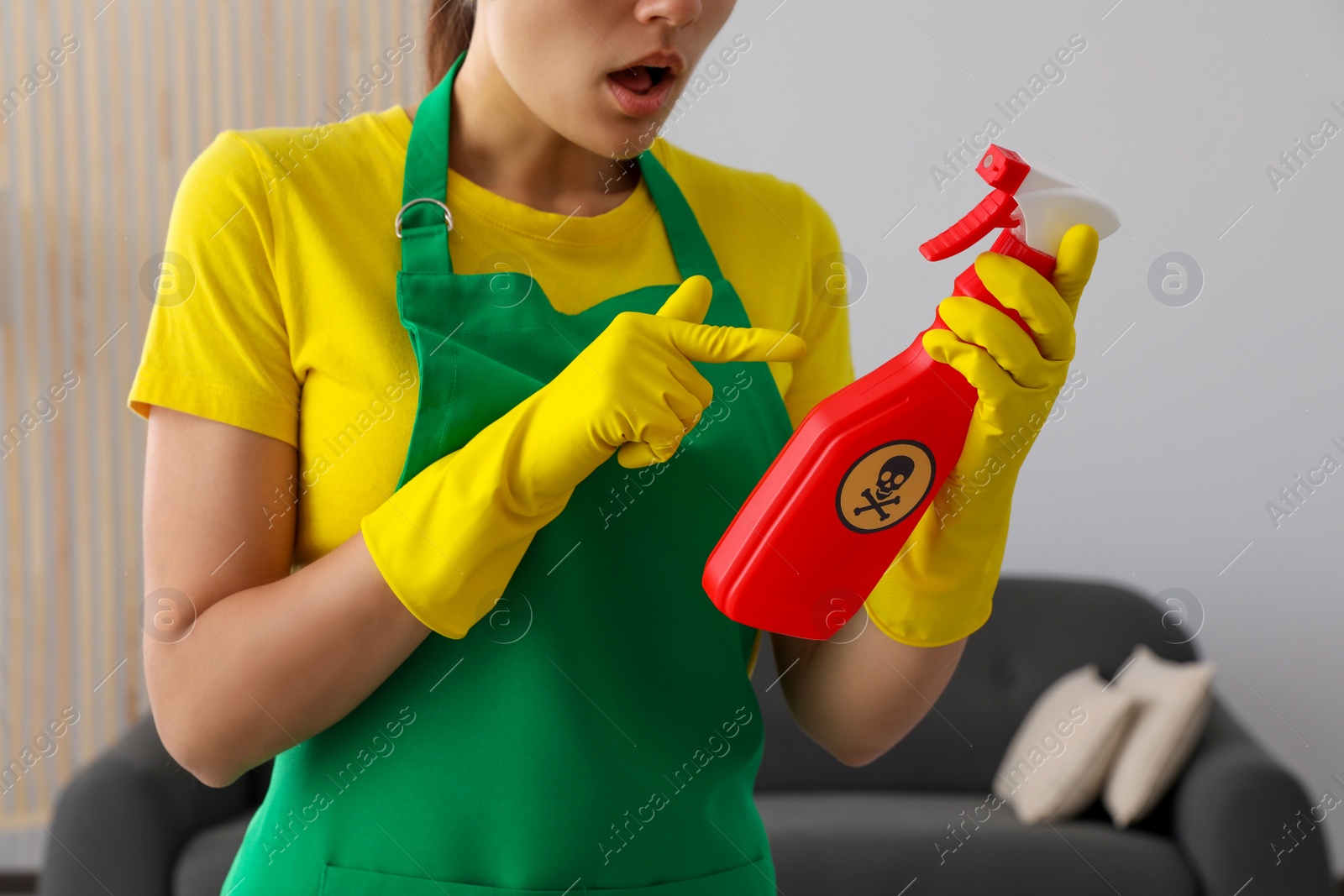 Photo of Woman pointing at bottle of toxic household chemical with warning sign, closeup