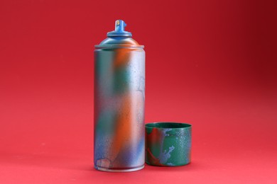 Photo of One can of bright spray paint with cap on red background