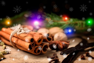 Different spices and fir tree branches on wooden table, closeup. Cinnamon, cloves, anise, cardamom, vanilla, nutmegs