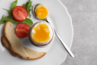 Photo of Breakfast with soft boiled egg on grey table, top view. Space for text