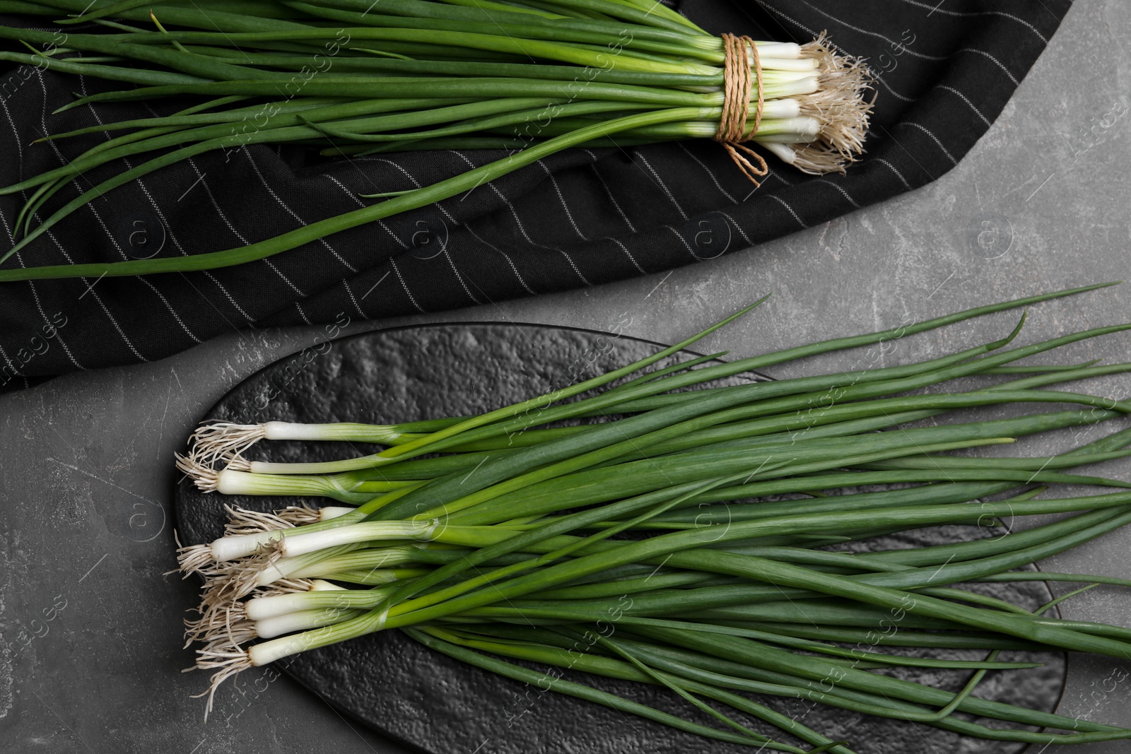 Photo of Fresh green spring onions on grey table, flat lay