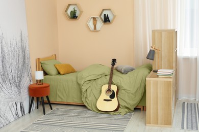 Photo of Stylish teenager's room interior with comfortable bed and guitar