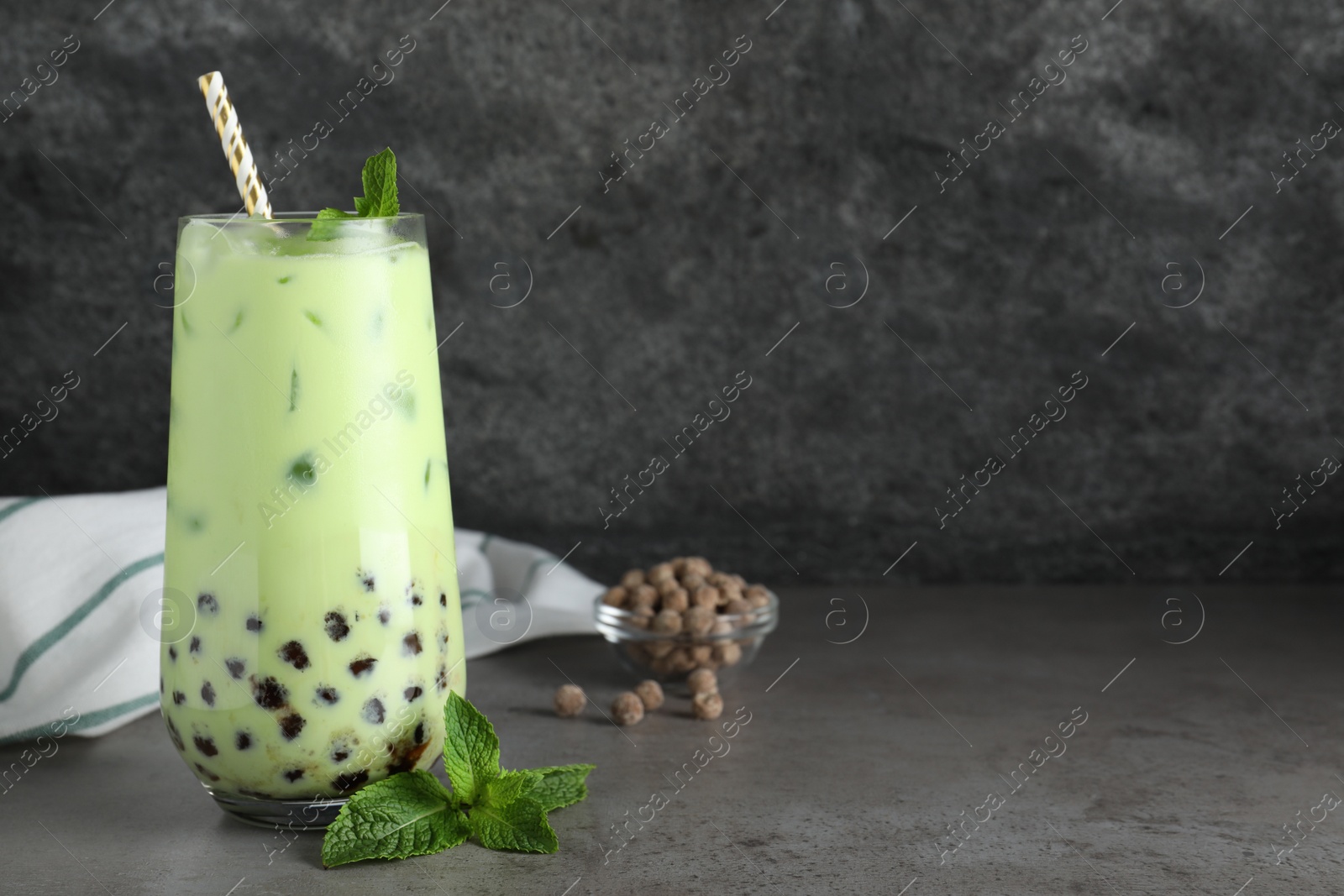 Photo of Tasty milk bubble tea with mint on light grey table. Space for text