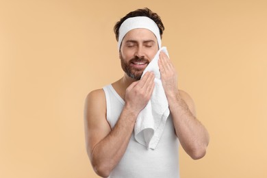 Photo of Washing face. Man with headband and towel on beige background