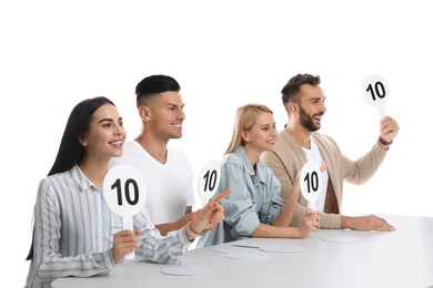 Panel of judges holding signs with highest score at table on white background