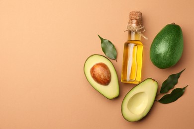 Photo of Glass bottle of cooking oil and fresh avocados on beige background, flat lay. Space for text