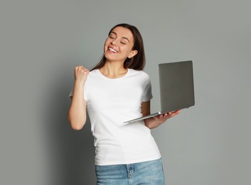 Photo of Young woman with modern laptop on grey background