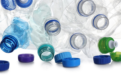 Pile of crumpled bottles and caps on white background, closeup. Plastic recycling