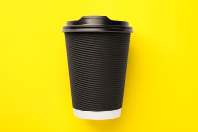 Photo of One paper cup on yellow background, top view. Coffee to go