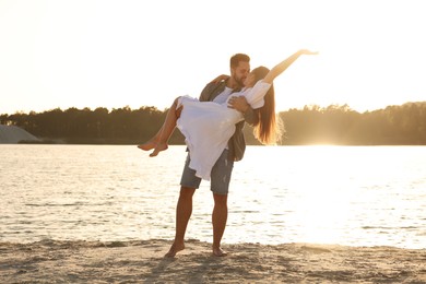 Photo of Beautiful couple dancing and kissing near river on sunny day
