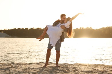 Beautiful couple dancing and kissing near river on sunny day