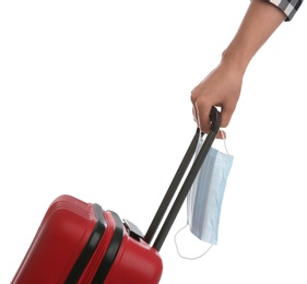 Woman with suitcase and protective mask on white background, closeup. Travelling during coronavirus pandemic