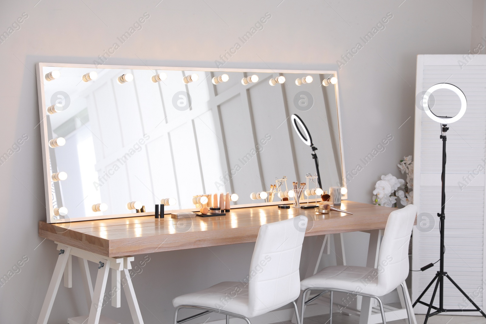 Photo of Modern mirror with light bulbs on dressing table in makeup room