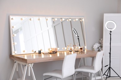 Modern mirror with light bulbs on dressing table in makeup room