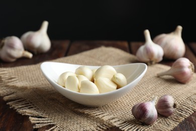 Photo of Fresh garlic cloves and bulbs on wooden table