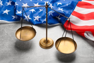 Photo of Scales of justice and American flag on light grey table