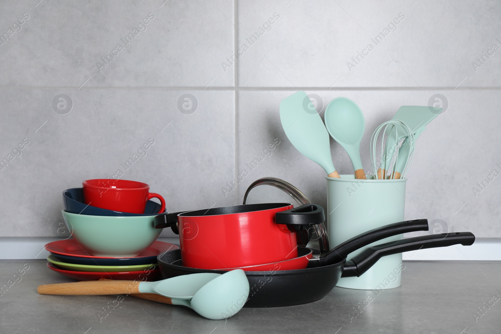 Photo of Set of cooking utensils and cookware on grey countertop