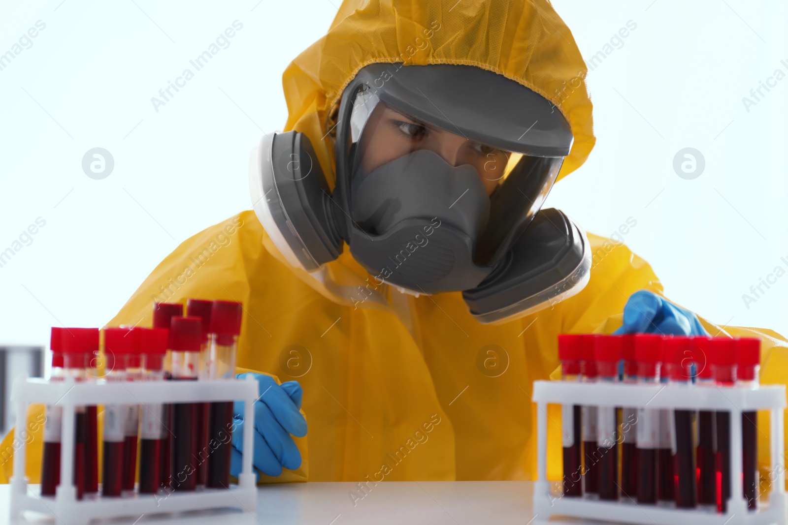 Photo of Scientist in chemical protective suit working with blood samples on white background. Virus research