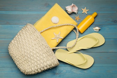 Photo of Stylish bag and beach accessories on blue wooden background, flat lay