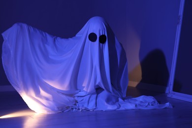 Photo of Creepy ghost. Woman covered with sheet in blue light