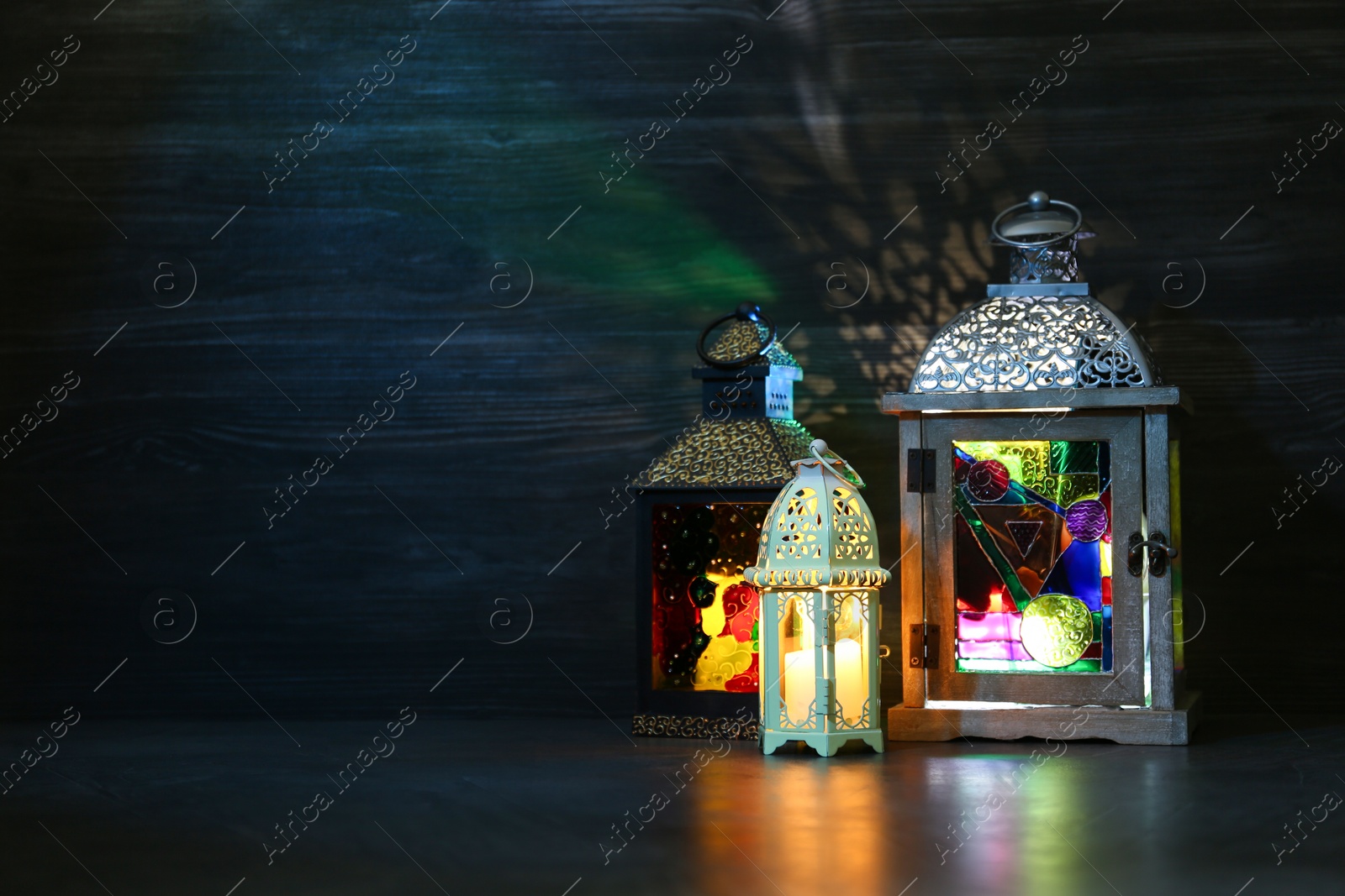 Photo of Decorative Arabic lanterns on table against dark background. Space for text