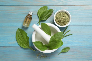 Photo of Fresh and dried broadleaf plantain leaves with essential oil on light blue wooden table, flat lay