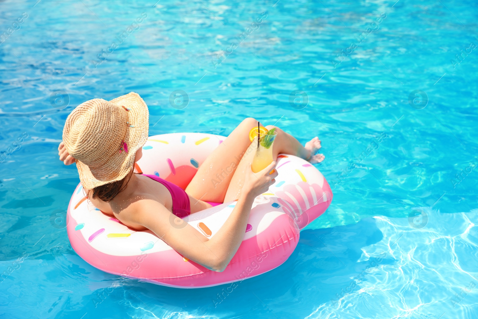 Photo of Young woman with cocktail in pool on sunny day