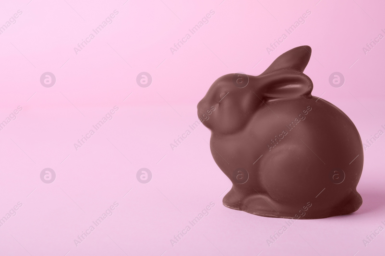 Photo of Chocolate bunny on pink background, space for text. Easter celebration