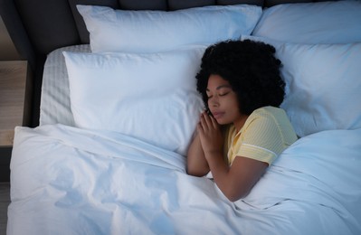 Photo of Young woman sleeping in soft bed at night, above view