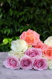 Photo of Beautiful bouquet of roses on light grey table outdoors, closeup