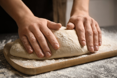 Photo of Woman beating dough at table, closeup. Making pasta