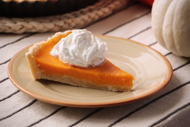 Piece of fresh homemade pumpkin pie with whipped cream on table