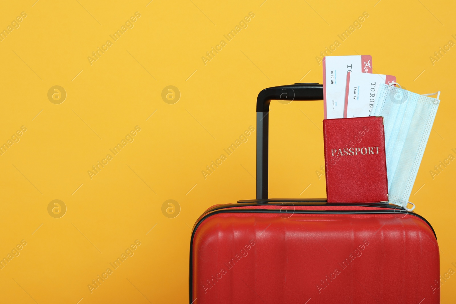 Photo of Passport with tickets and protective mask on suitcase against yellow background, space for text. Travel during quarantine