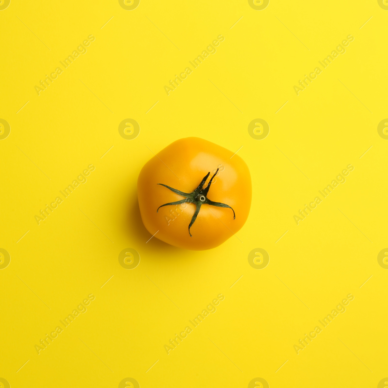 Photo of Yellow tomato on color background, top view